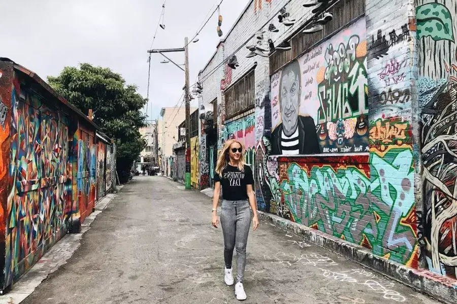 A woman walks through an alley in the Mission District that is covered with murals and artwork. San Francisco, California.